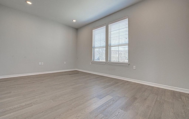 unfurnished room with recessed lighting, wood finished floors, and baseboards