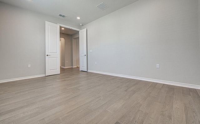 spare room with baseboards, visible vents, and wood finished floors