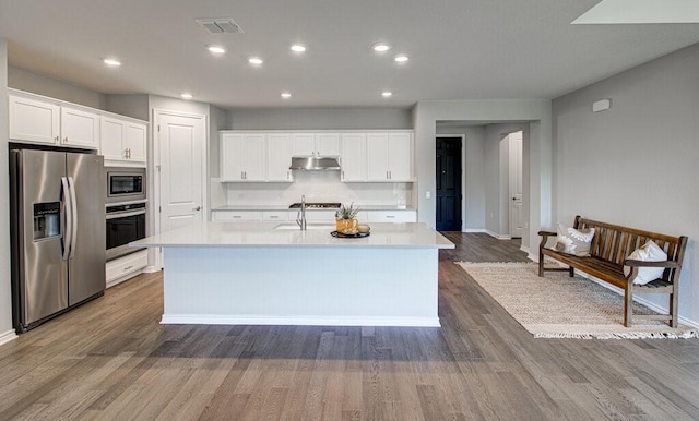 128 Roaming Rock Trl Unit 102, San Marcos, TX 78666 - kitchen featuring appliances with stainless steel finishes, under cabinet range hood, light countertops, wood finished floors, and recessed lighting