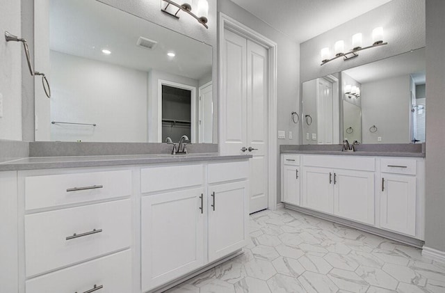 bathroom with two vanities, marble finish floor, visible vents, and a sink