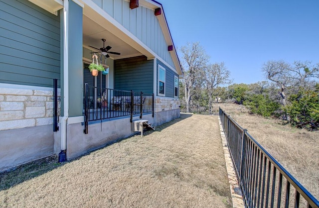 view of property exterior with stone siding, board and batten siding, fence, and a ceiling fan