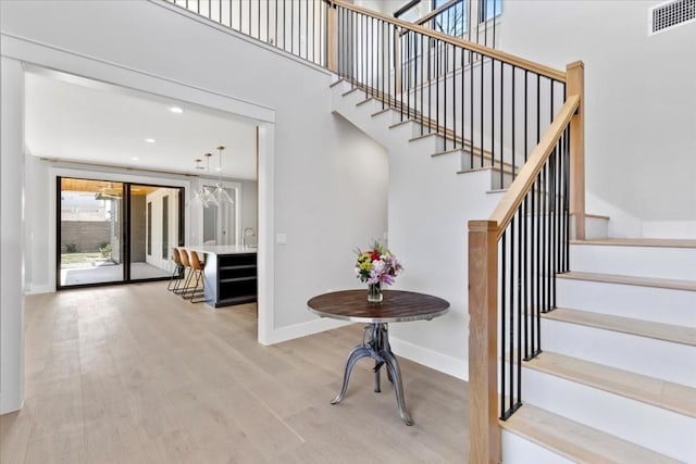 stairs with sink, hardwood / wood-style floors, and a high ceiling