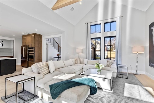 living room with beamed ceiling, high vaulted ceiling, and light hardwood / wood-style flooring