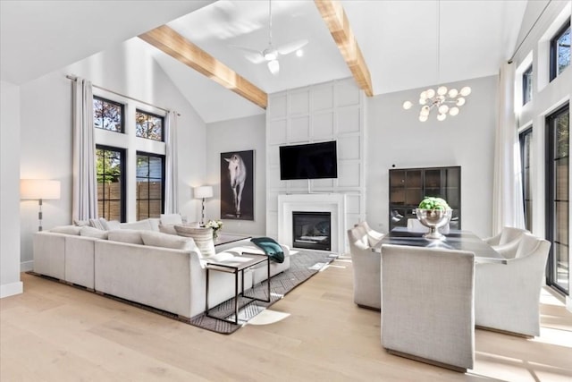 living room featuring beam ceiling, high vaulted ceiling, a notable chandelier, a fireplace, and light hardwood / wood-style floors