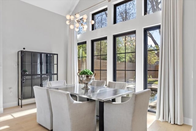 dining room featuring high vaulted ceiling, a chandelier, and light wood-type flooring