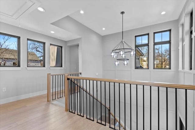 hallway with an inviting chandelier, light hardwood / wood-style floors, and a healthy amount of sunlight