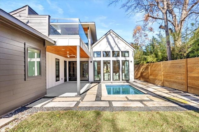 rear view of property featuring ceiling fan, a fenced in pool, and a patio