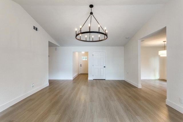 interior space featuring hardwood / wood-style flooring, lofted ceiling, and a notable chandelier