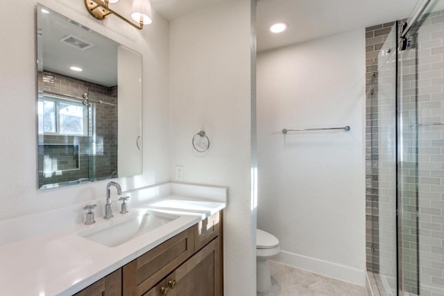 bathroom with a shower with door, vanity, tile patterned floors, and toilet