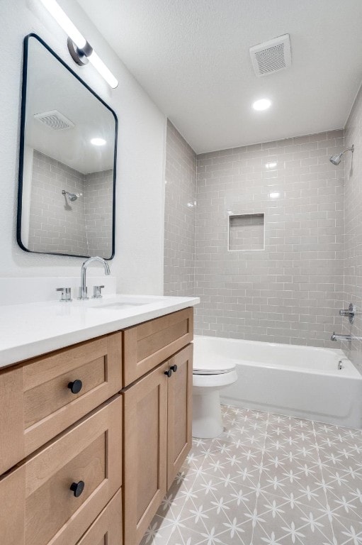 full bathroom with tiled shower / bath, vanity, toilet, and a textured ceiling