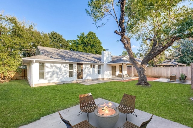 back of property with a yard, a patio area, and a fire pit