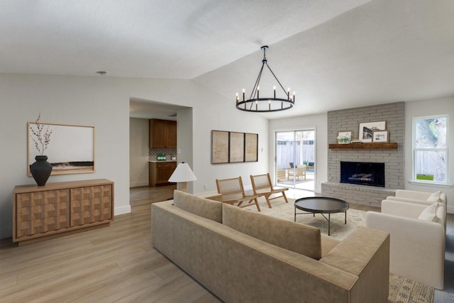 living room featuring lofted ceiling, a fireplace, light hardwood / wood-style floors, and plenty of natural light