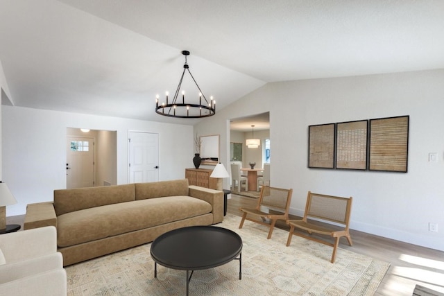 living room with an inviting chandelier, vaulted ceiling, and light hardwood / wood-style floors