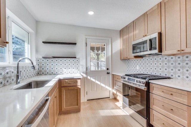 kitchen featuring appliances with stainless steel finishes, light brown cabinetry, sink, and light wood-type flooring