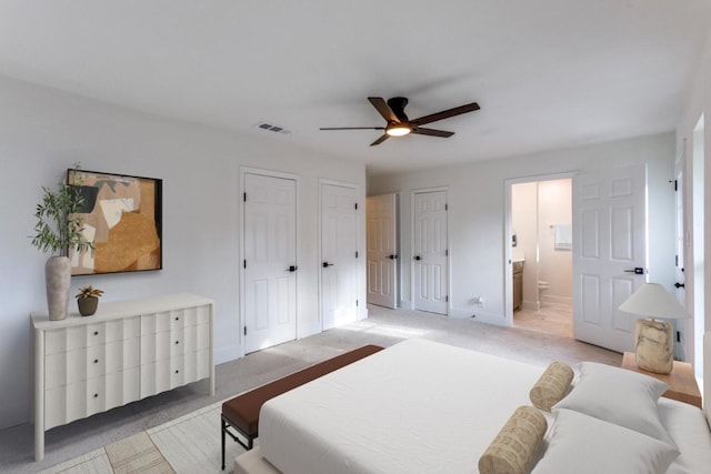 carpeted bedroom featuring multiple closets, ceiling fan, and connected bathroom