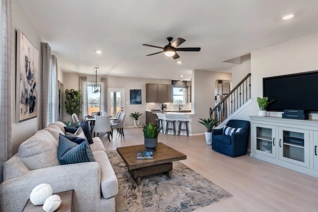 living room with ceiling fan, sink, and light hardwood / wood-style flooring