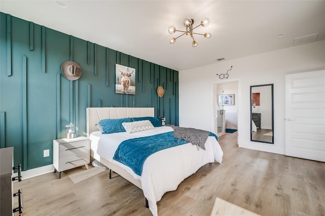 bedroom featuring a chandelier, light wood-style flooring, and baseboards