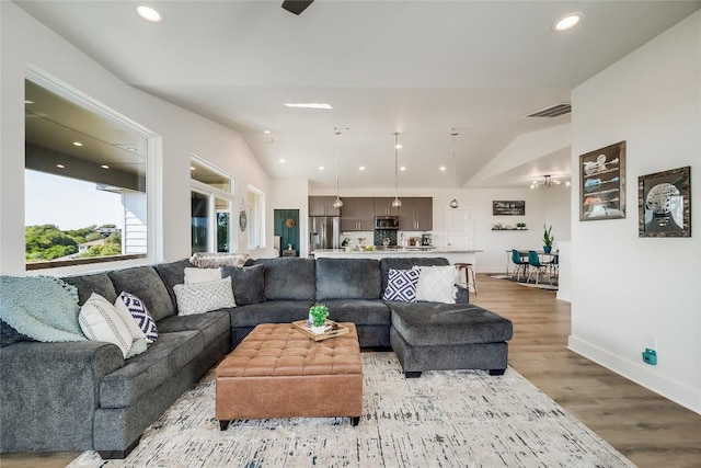 living area featuring light wood finished floors, recessed lighting, baseboards, and lofted ceiling