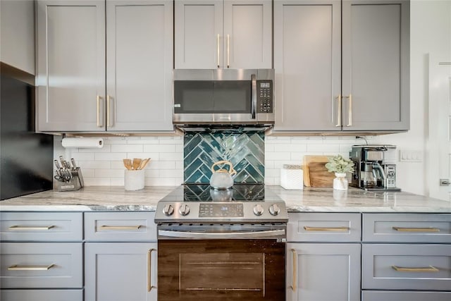 kitchen featuring stainless steel appliances, gray cabinets, and light stone counters