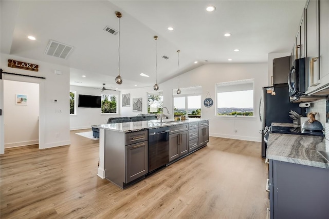 kitchen with gray cabinets, pendant lighting, dishwashing machine, light stone counters, and a barn door