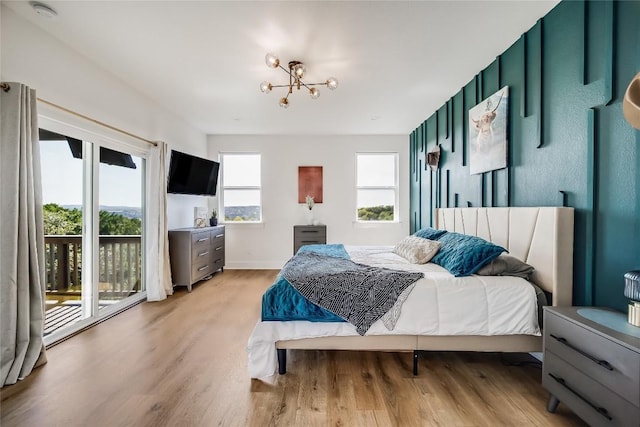 bedroom featuring a chandelier, light wood finished floors, access to exterior, and baseboards