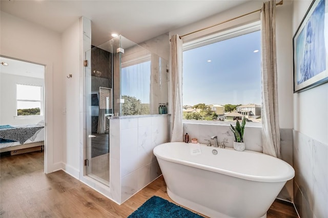 bathroom featuring plenty of natural light, plus walk in shower, and wood-type flooring