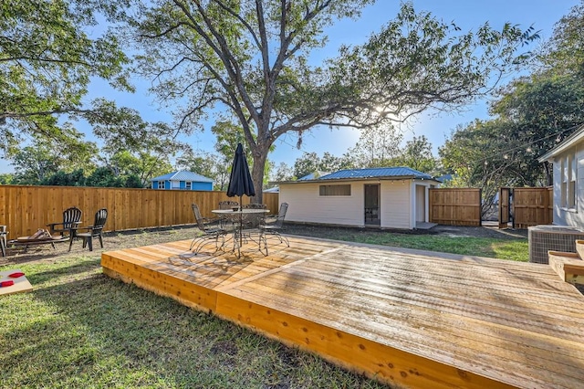 deck featuring an outdoor structure, a lawn, central AC unit, and a fire pit