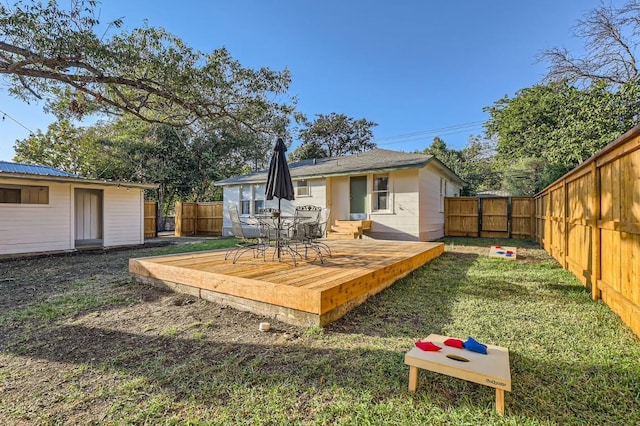 rear view of house featuring a wooden deck and a yard