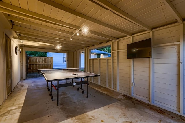 rec room with beam ceiling and concrete floors