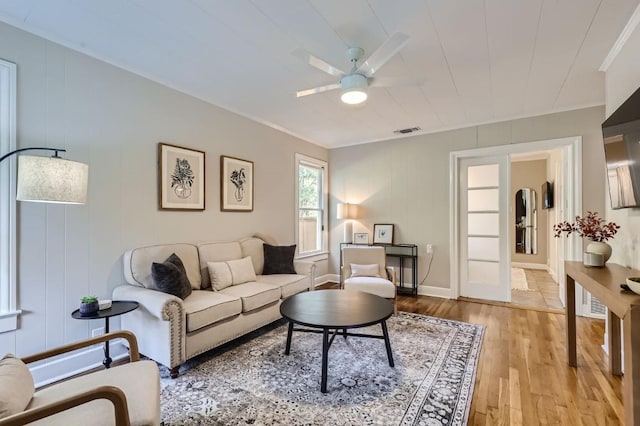 living room with ornamental molding, ceiling fan, and light hardwood / wood-style flooring