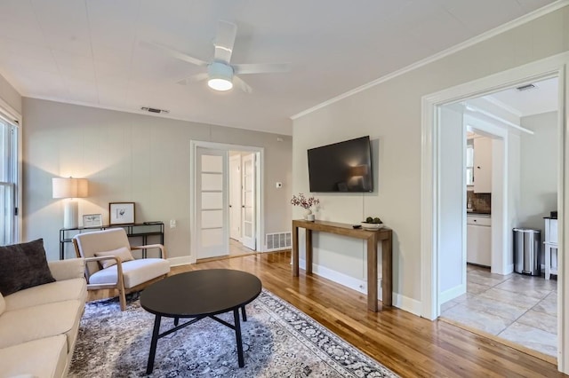 living room featuring ceiling fan, ornamental molding, and light wood-type flooring