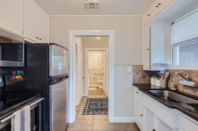 kitchen featuring sink, tasteful backsplash, light tile patterned floors, appliances with stainless steel finishes, and white cabinets