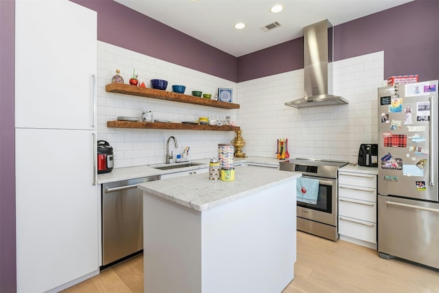 kitchen featuring wall chimney range hood, sink, stainless steel appliances, a center island, and light hardwood / wood-style floors