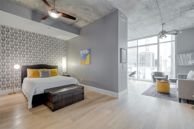 bedroom with a ceiling fan, expansive windows, baseboards, and wood finished floors