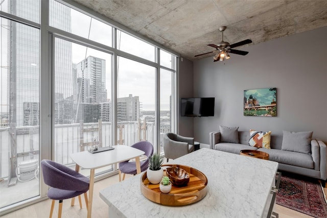 living area with light wood-style floors, floor to ceiling windows, and a ceiling fan