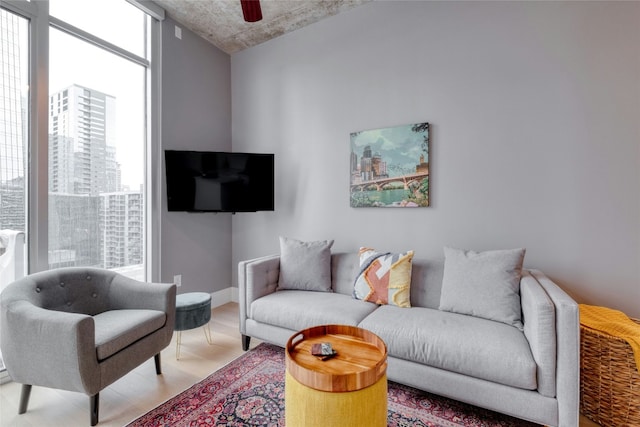 living area featuring ceiling fan, expansive windows, and light wood-style flooring