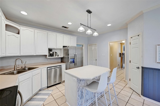 kitchen with sink, appliances with stainless steel finishes, white cabinetry, a center island, and decorative light fixtures