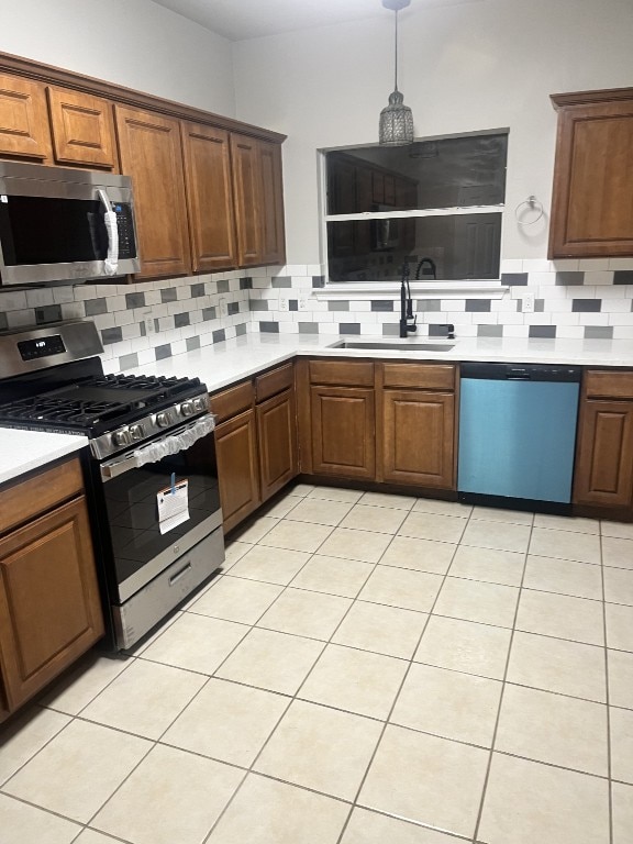 kitchen with pendant lighting, sink, light tile patterned floors, appliances with stainless steel finishes, and tasteful backsplash