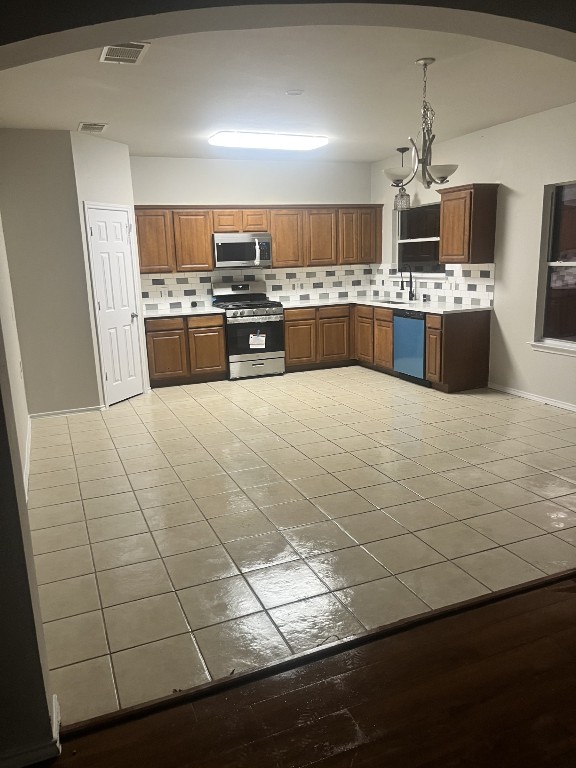 kitchen with sink, hanging light fixtures, light tile patterned floors, stainless steel appliances, and backsplash