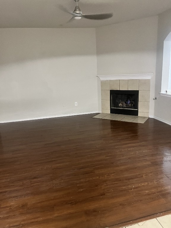 unfurnished living room featuring dark wood-type flooring, a tile fireplace, and ceiling fan