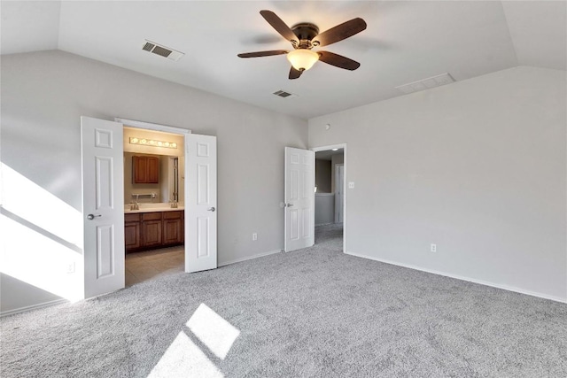 unfurnished bedroom with connected bathroom, vaulted ceiling, light colored carpet, and ceiling fan