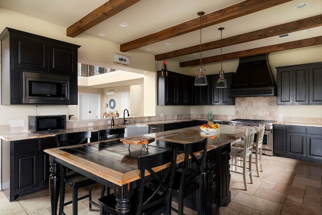 kitchen featuring premium range hood, sink, a breakfast bar area, hanging light fixtures, and appliances with stainless steel finishes