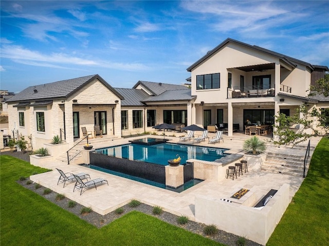 back of property with a patio area, a balcony, and an outdoor fire pit