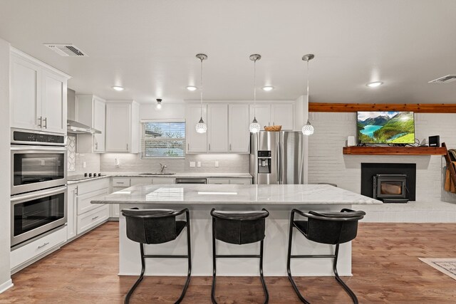 kitchen with a kitchen bar, white cabinetry, a kitchen island, pendant lighting, and stainless steel appliances