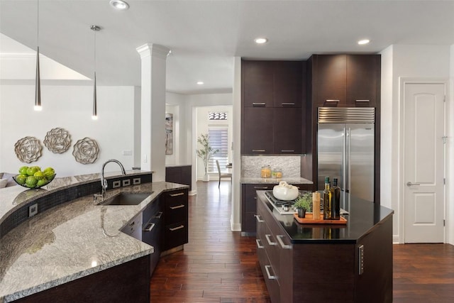 kitchen featuring pendant lighting, sink, dark wood-type flooring, dark brown cabinets, and stainless steel built in refrigerator