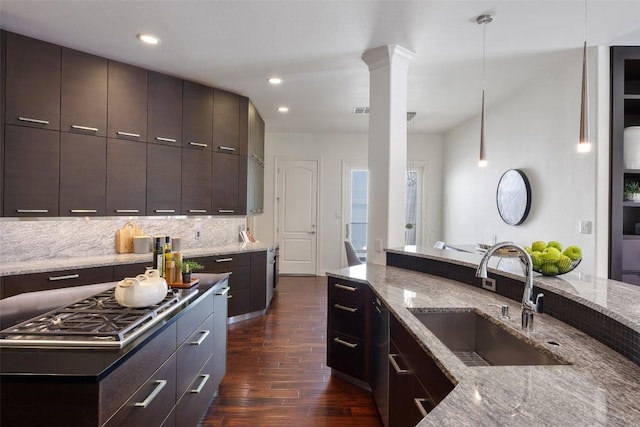 kitchen featuring dark wood-type flooring, sink, tasteful backsplash, dark brown cabinets, and decorative columns