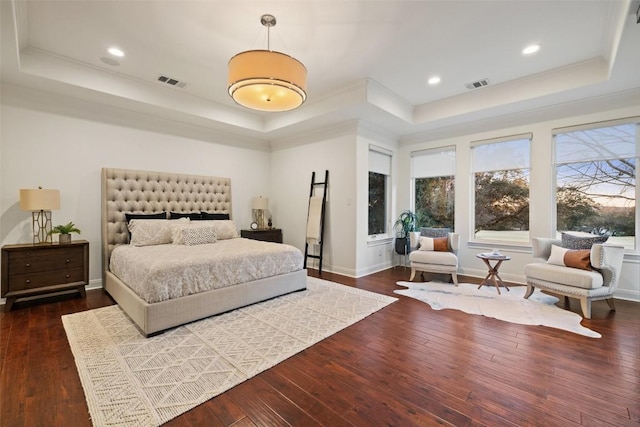 bedroom with dark hardwood / wood-style flooring, ornamental molding, and a raised ceiling