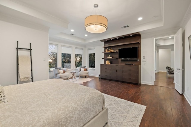 bedroom with dark hardwood / wood-style floors, ornamental molding, and a tray ceiling