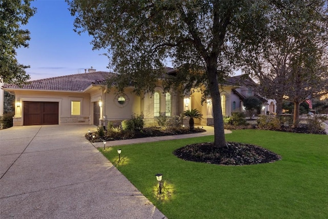 mediterranean / spanish-style home featuring a garage and a lawn