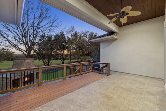 deck at dusk featuring exterior fireplace and ceiling fan